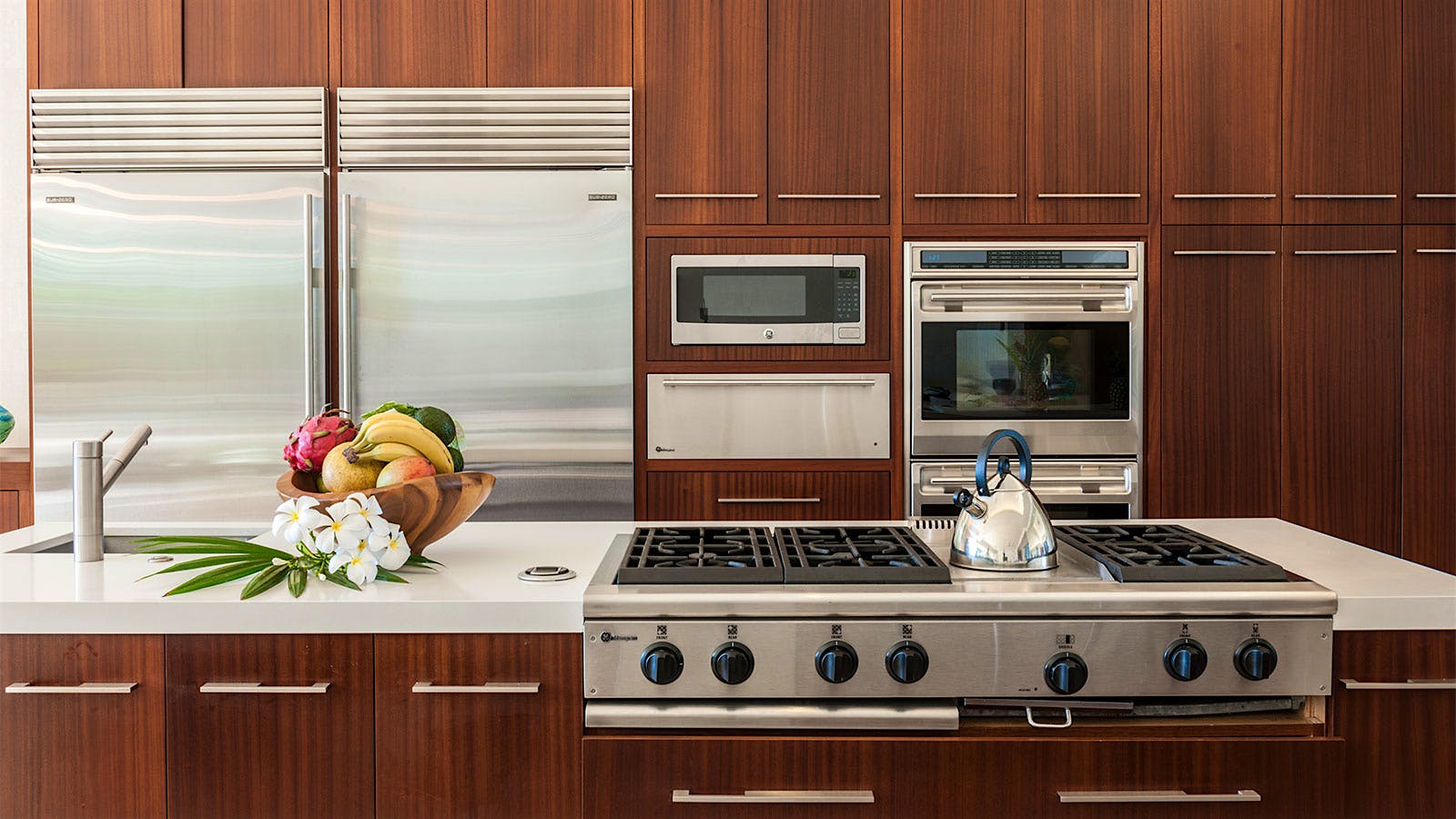 The orderly kitchen features teak cabinetry, a GE Monogram range and warming drawer, Sub-Zero fridge and Wolf microwave.